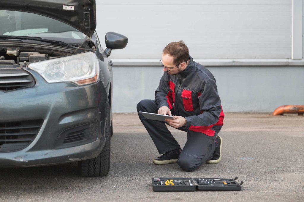 digital vehicle service history, technician inspecting tyre with tablet in hand