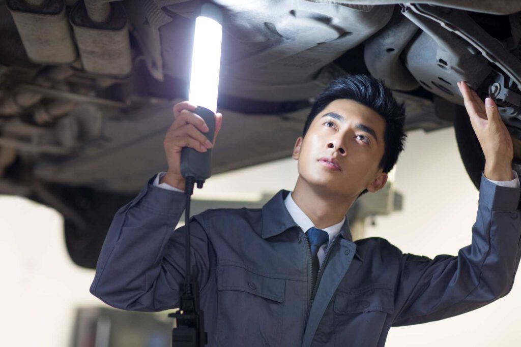 how to upgrade your garage, mechanic holding hand light against base of car
