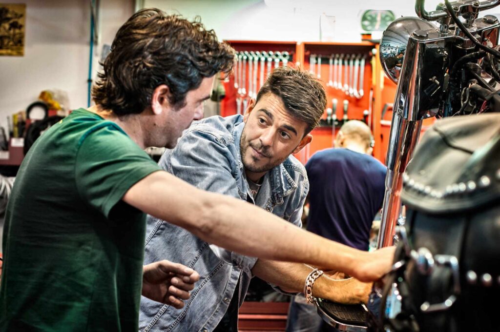 streamline car repair, older garage worker helping younger garage mechanics