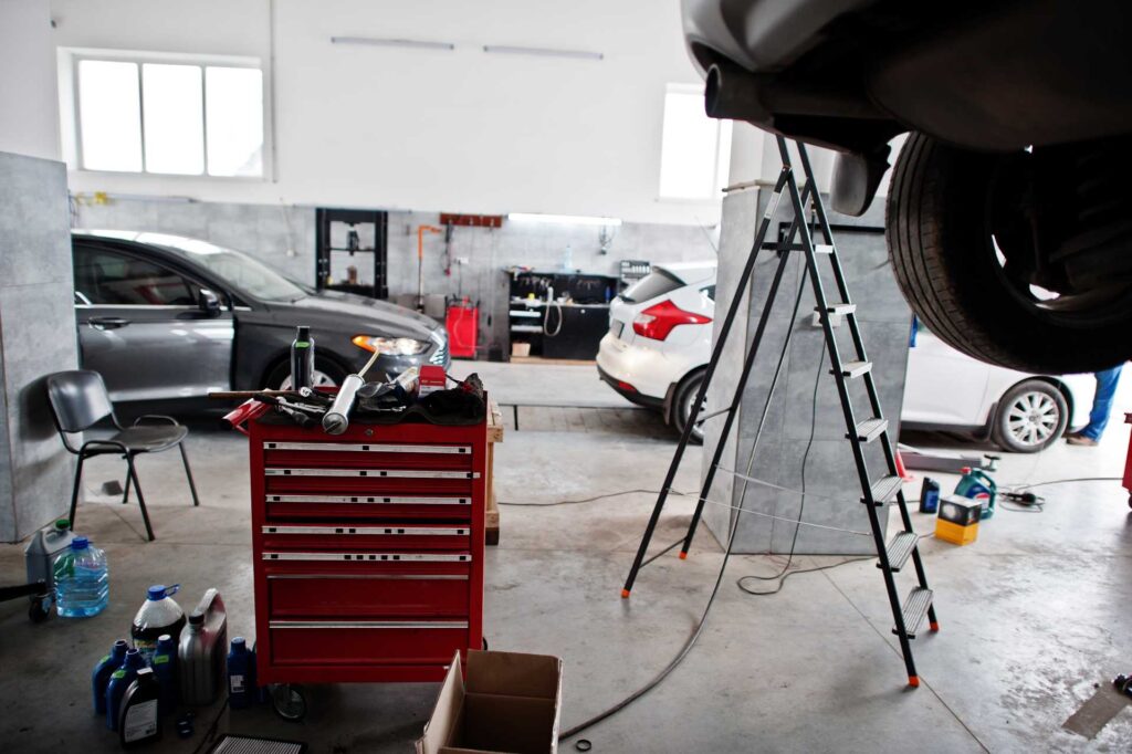 auto repair shop design, lifted car with mechanic's table of tools beside it
