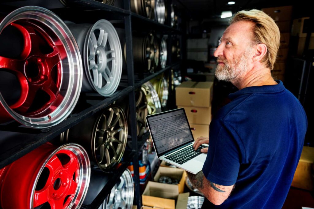 setting up a garage, garage technician using computer behind car wheels
