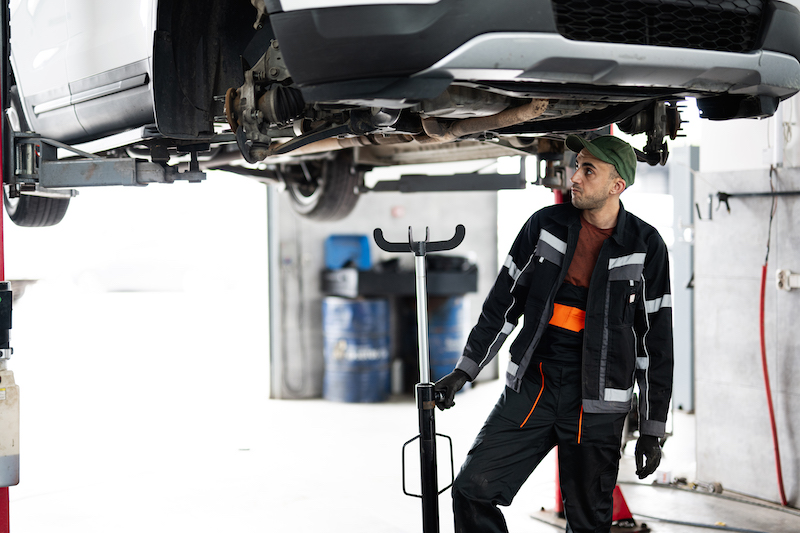 Garage scheduling software, mechanic under a lifted car.